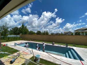workers from a pool finishing company spraying plaster finish on
